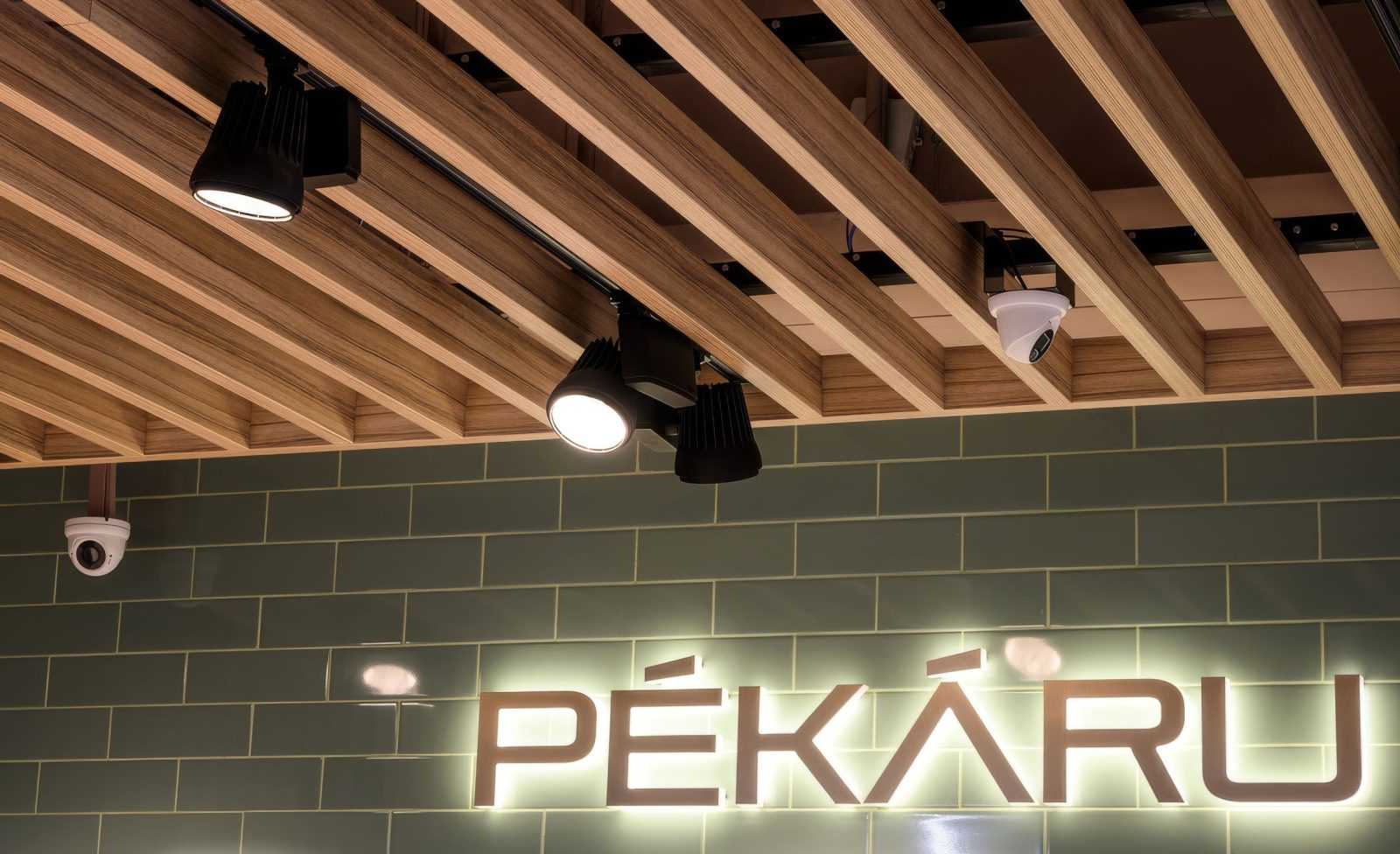 Modern wooden ceiling with lights and 'PÉKÁRU' sign.