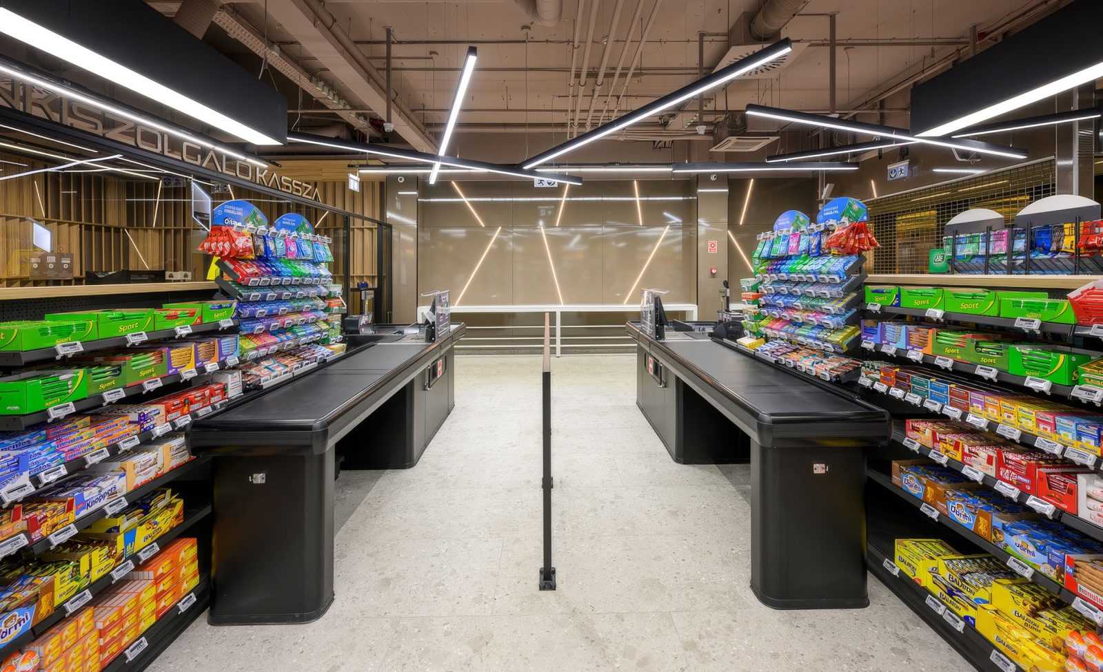 Modern supermarket checkout area with bright lighting and colorful candy shelves.