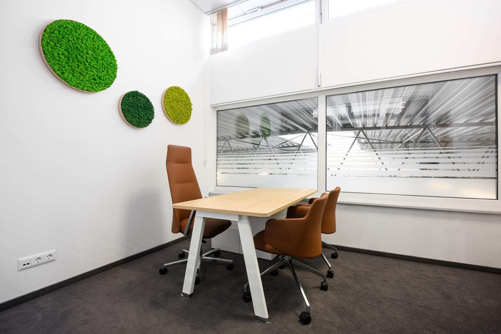 Modern office meeting room with green wall decor and wooden table.