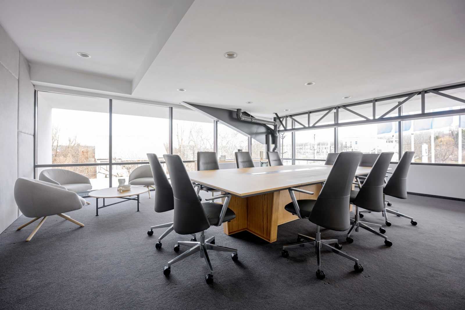 Modern conference room with wooden table and gray chairs.