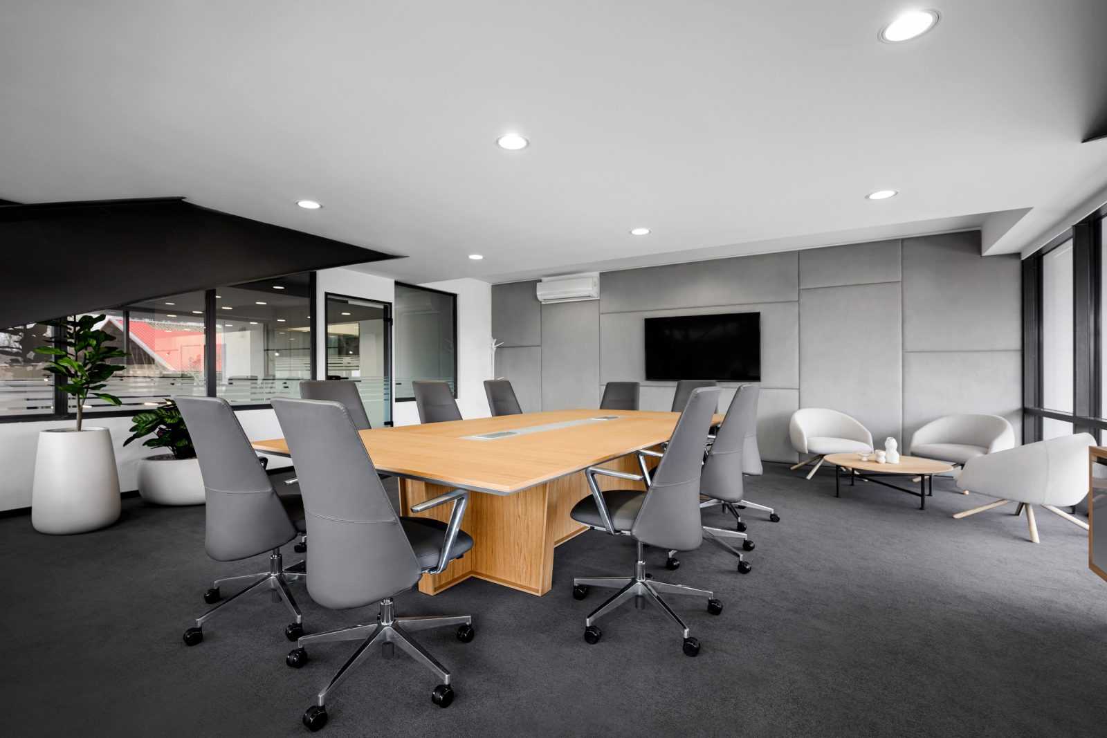 Modern conference room with wooden table and gray chairs.
