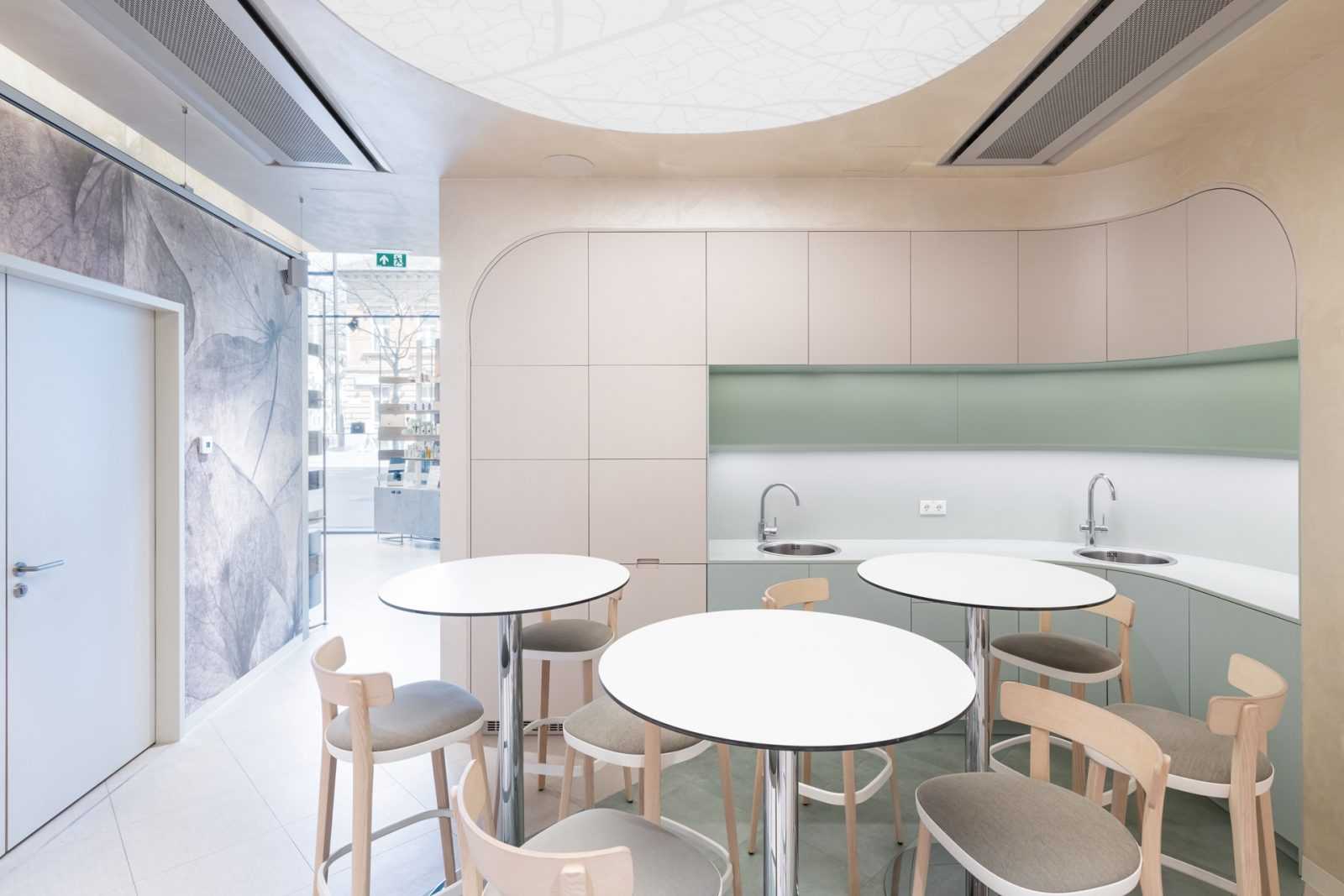 Modern minimalist interior with round tables and chairs, curved cabinetry, and leaf-patterned wall.