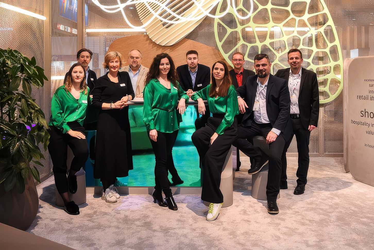 Megaholz team posing at trade show with modern design backdrop.