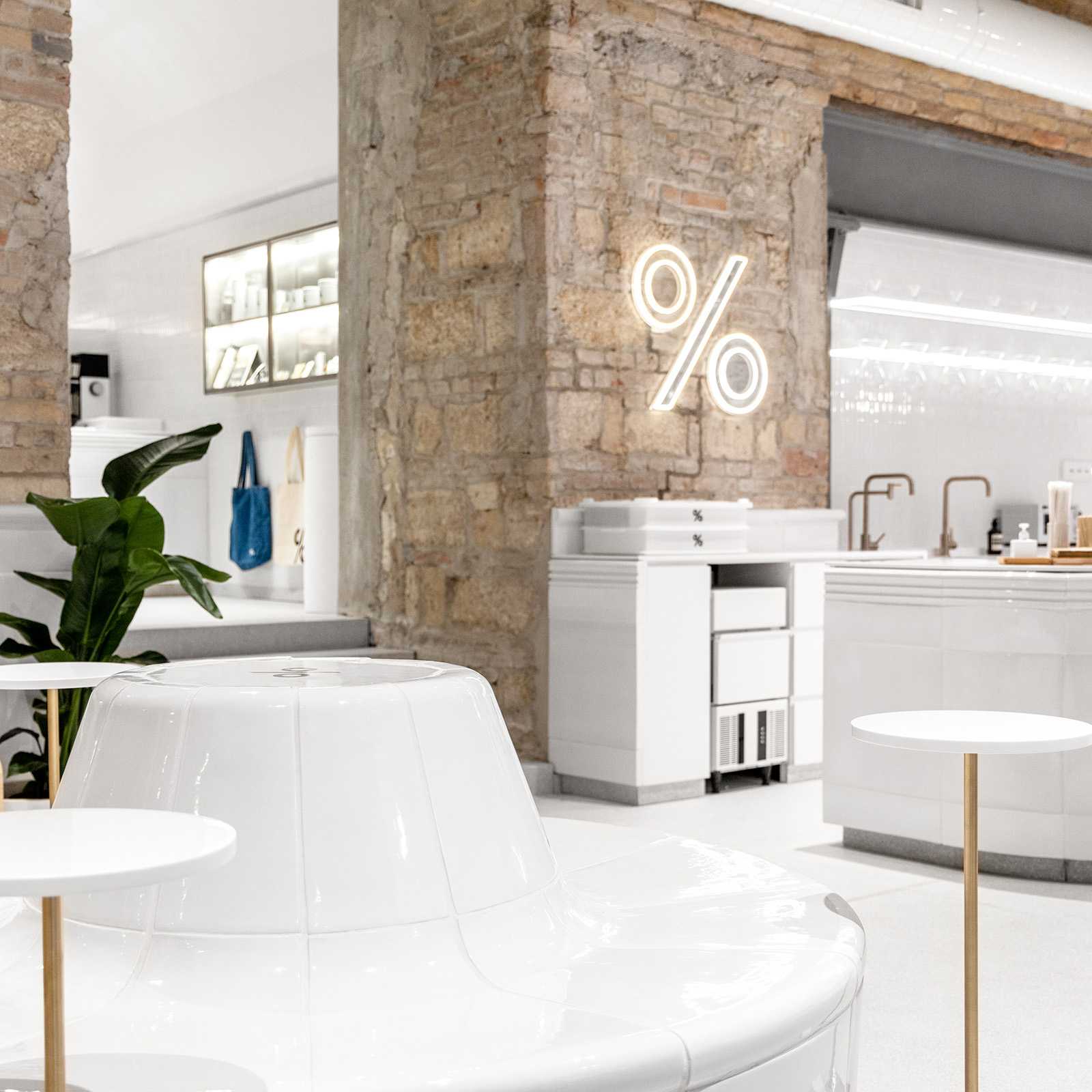 Modern minimalist cafe interior with neon % sign on brick wall.
