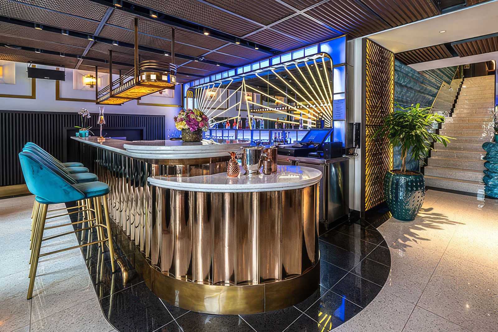 Luxury bar with gold accents and blue velvet stools.