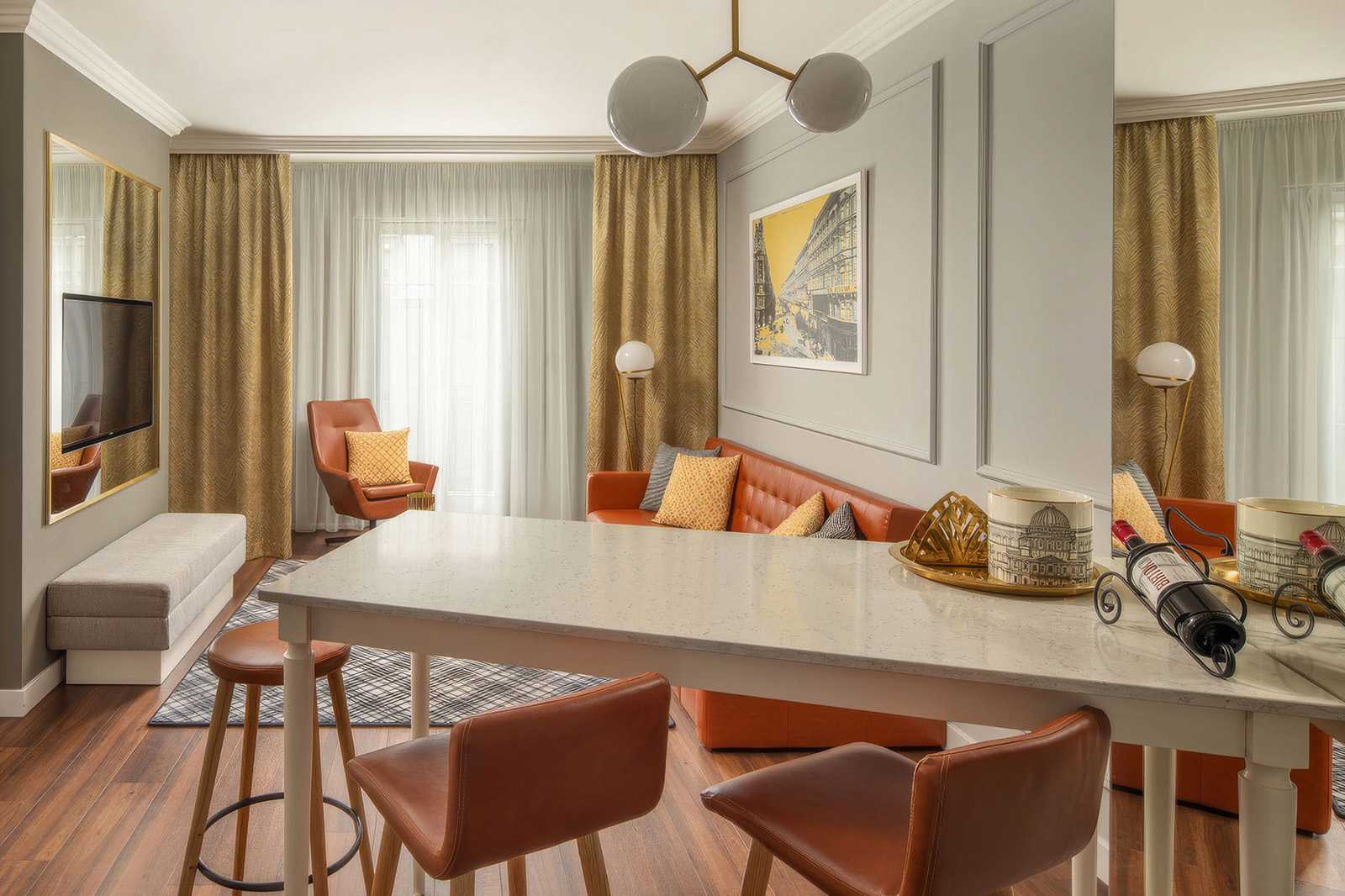 Modern hotel room with orange leather seating and marble dining table.