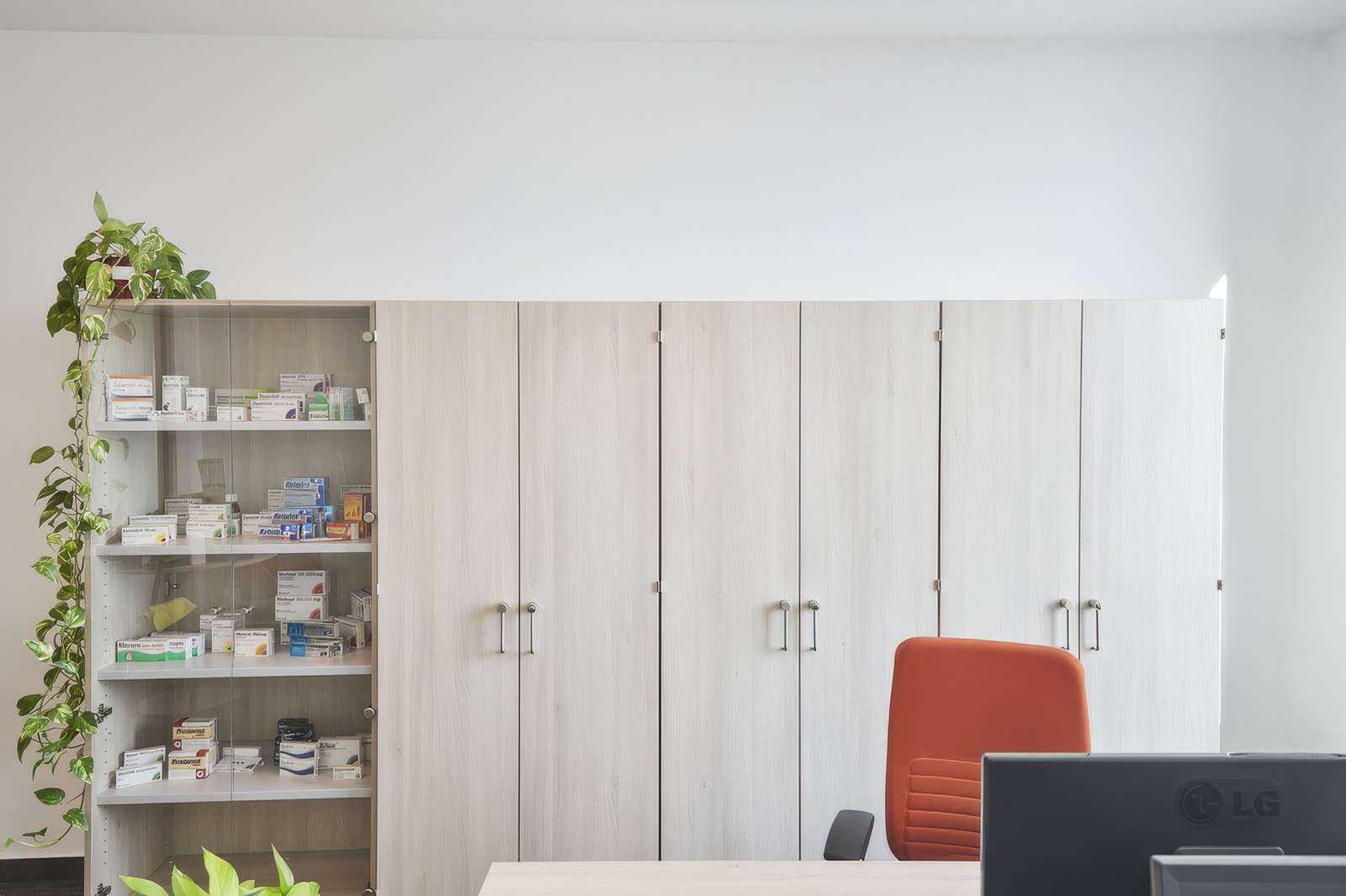 Modern pharmacy office with medicine cabinets and orange chair.