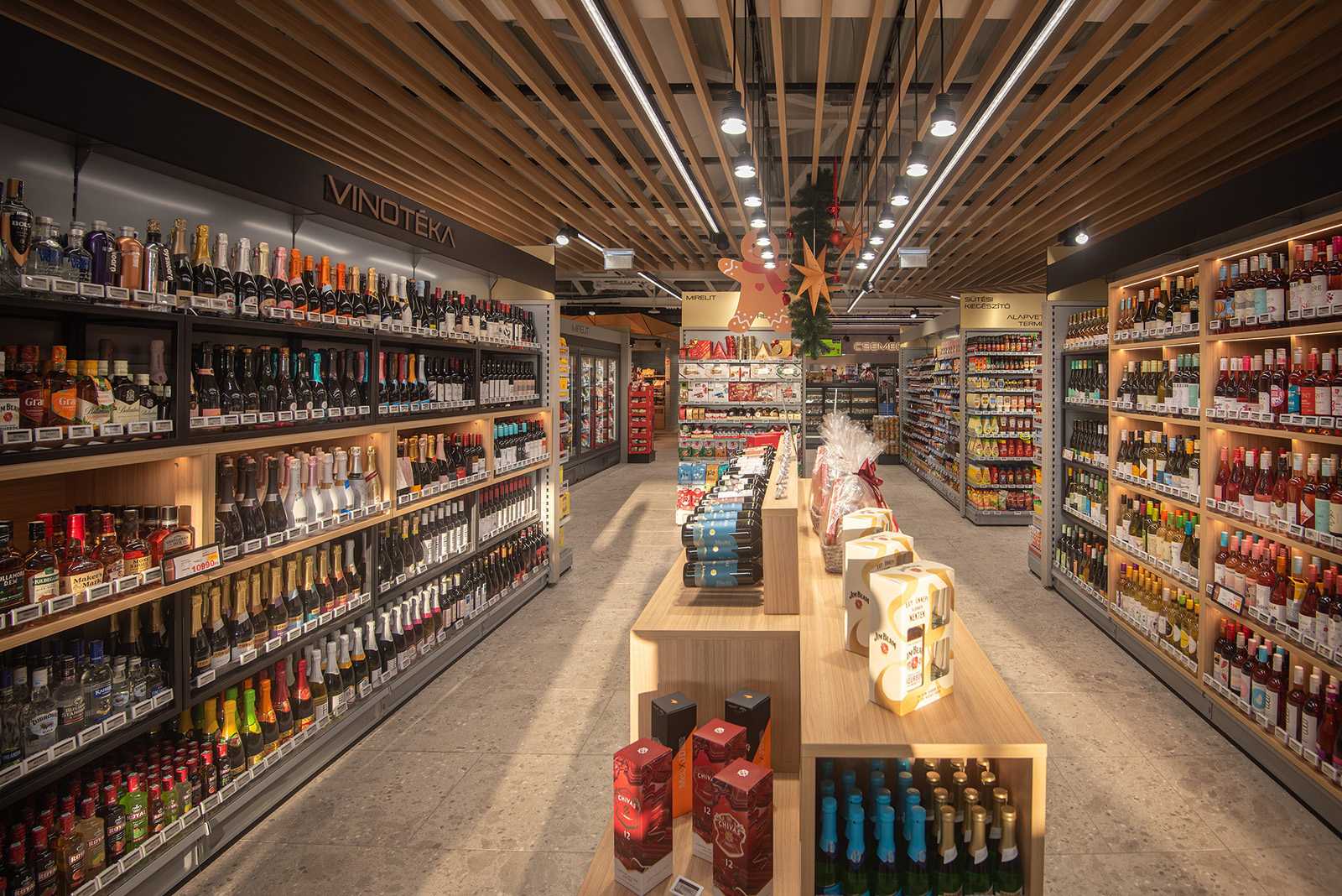 Modern wine and spirits store interior with wooden shelves and festive decorations.