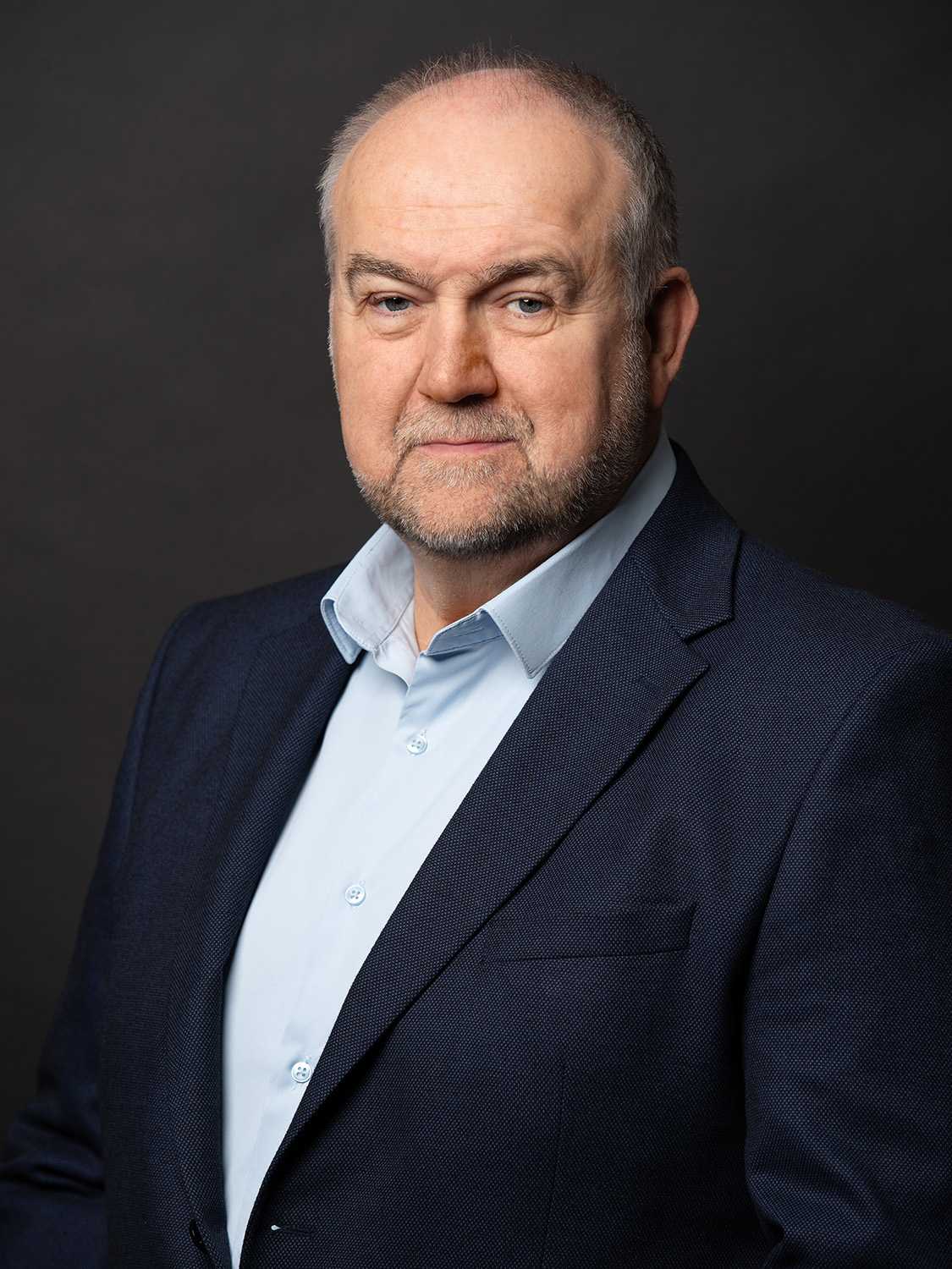 Professional headshot of a man in suit and light blue shirt.