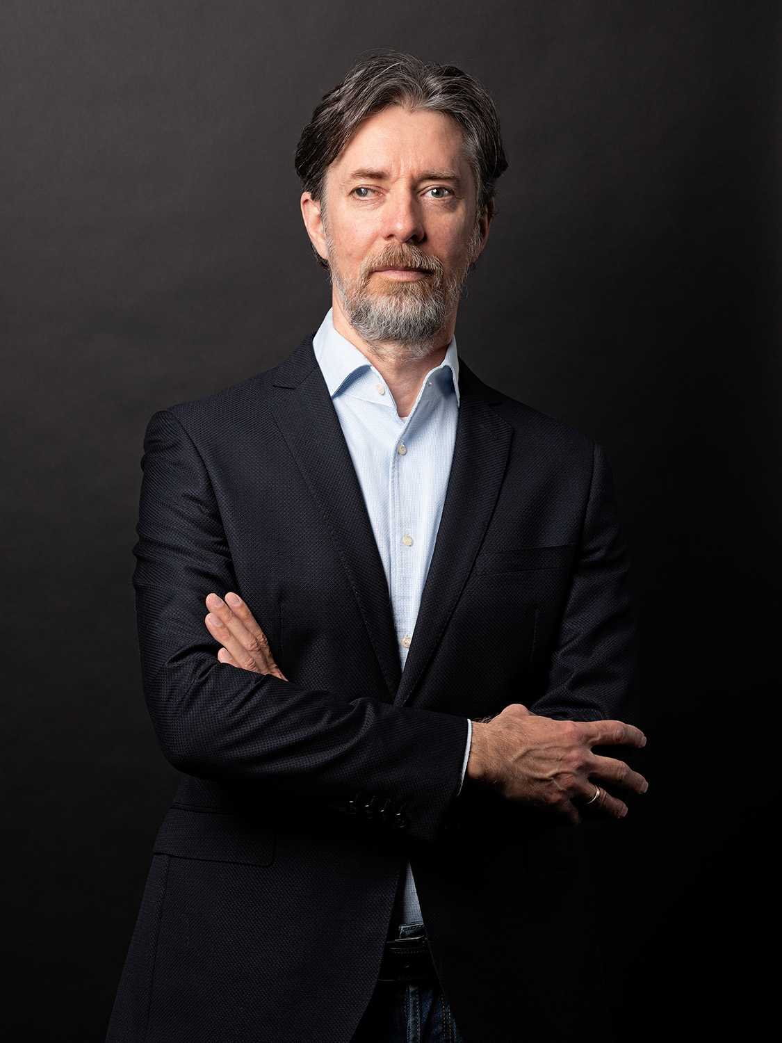 Professional portrait of a man in suit with arms crossed.