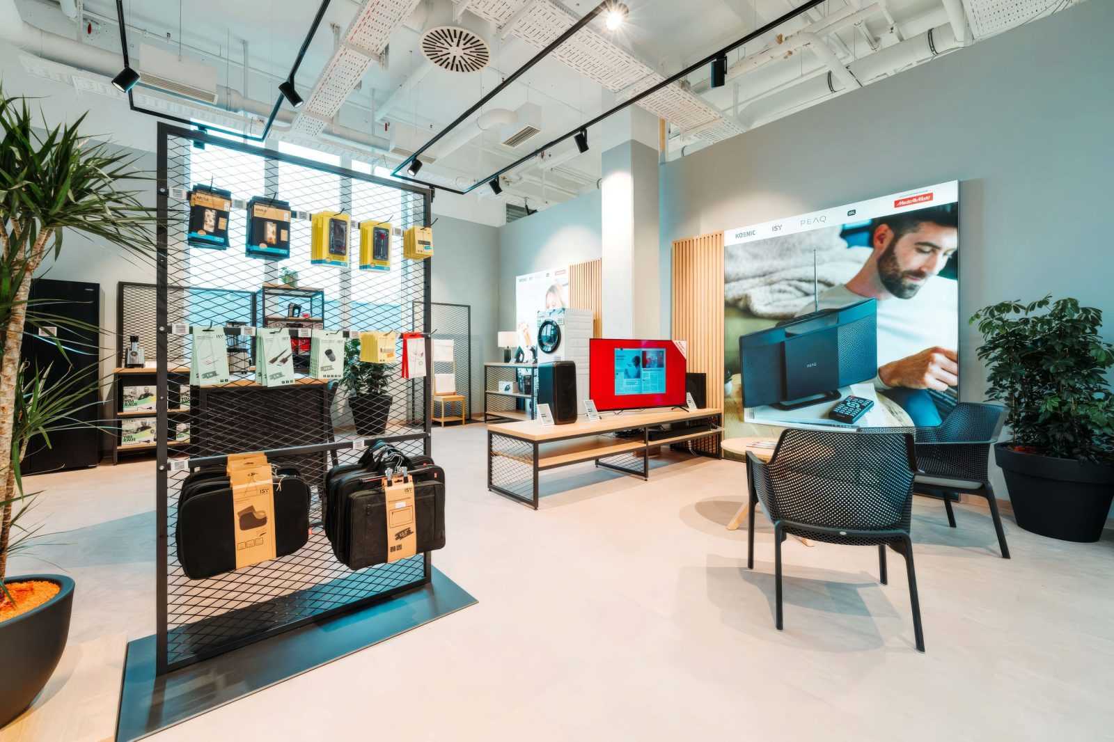 Modern electronics store interior with TVs, speakers, and home appliances on display.