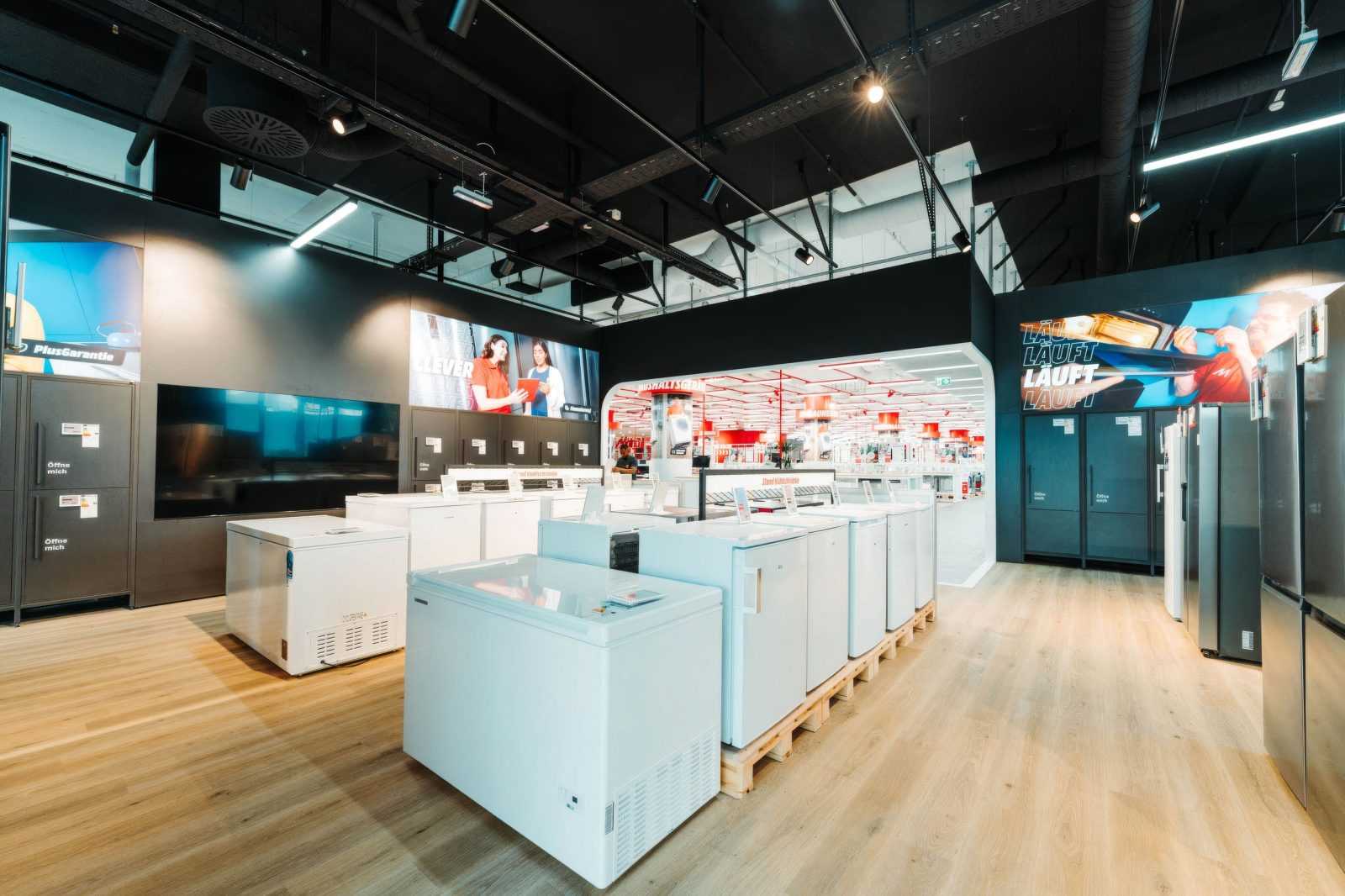 Modern appliance store interior with refrigerators and freezers on display.