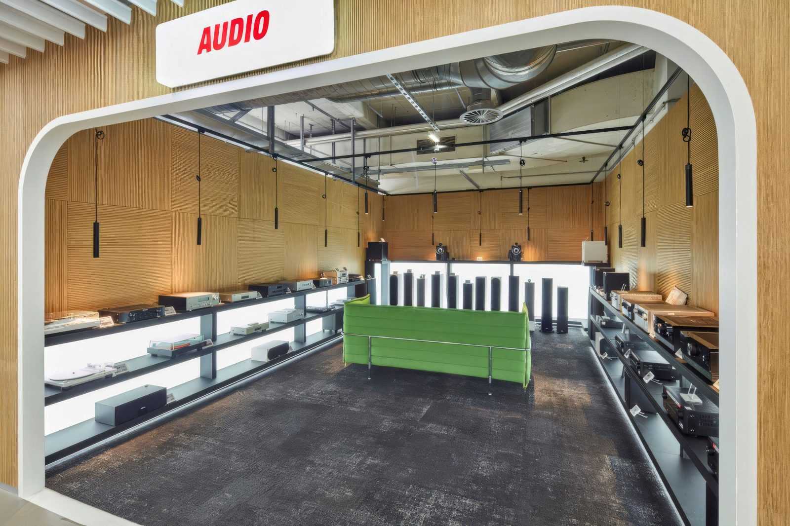 Modern audio equipment store with wooden walls and green sofa.