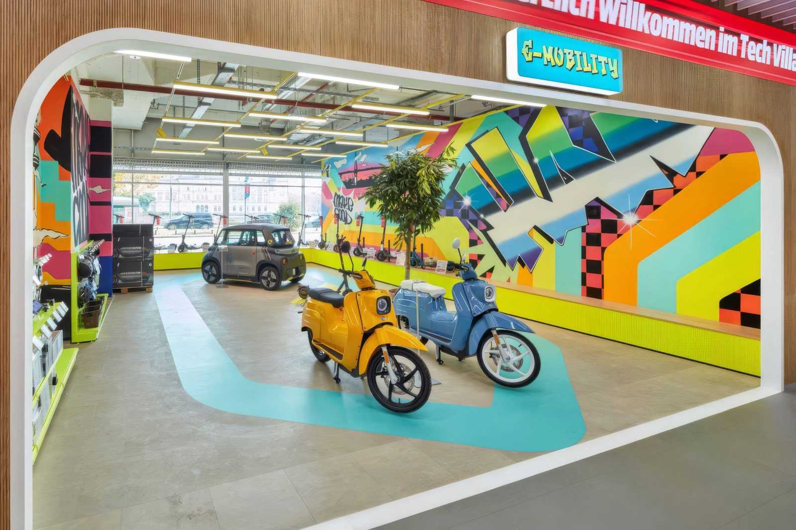 Electric scooters and car on display in vibrant e-mobility showroom.