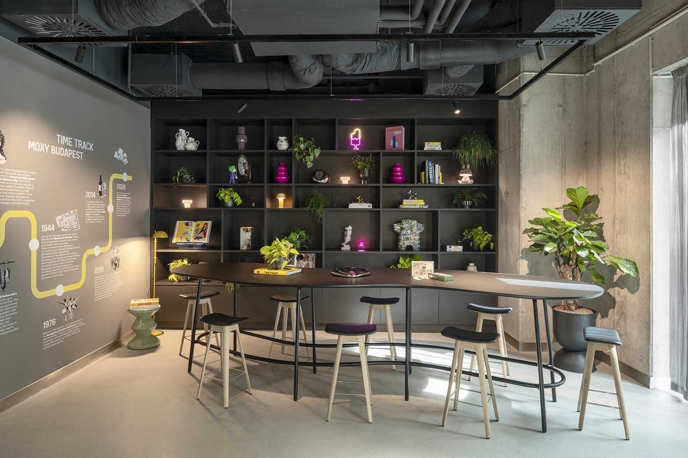 Modern industrial office lounge with curved bar, bookshelves, and time track wall.