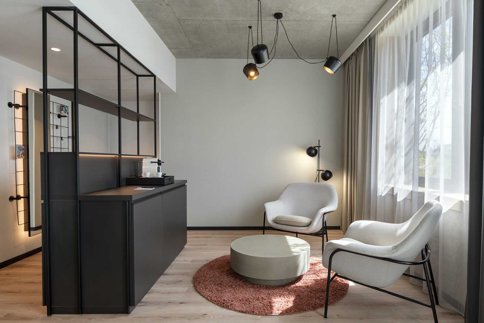 Modern minimalist living room with sleek furniture and industrial lighting.