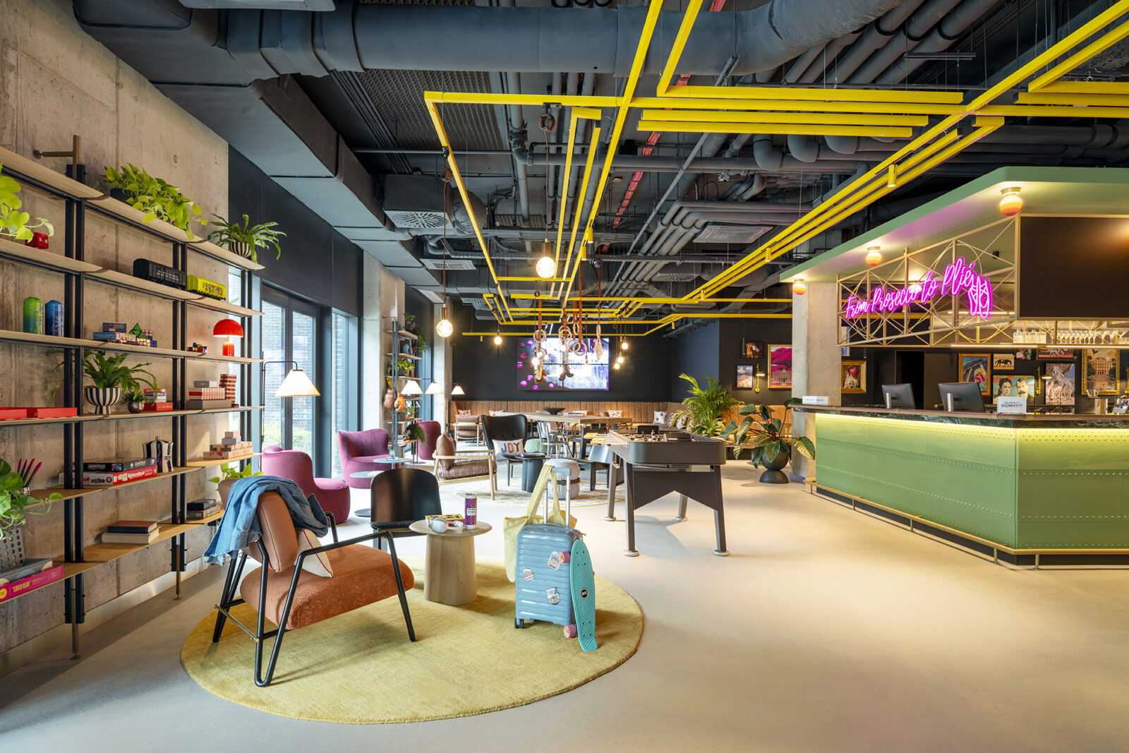 Modern hotel lobby with colorful furniture and neon sign.